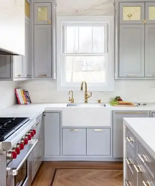 회색 캐비닛과 황동 탭이 있는 흰색 집사 싱크대가 있는 현대적인 주방