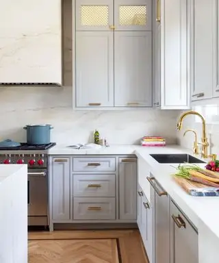 moderná kuchyňa so sivými skrinkami a bielymi doskami a zlatým kovaním