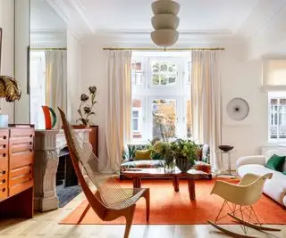 sala de estar ecléctica con paredes neutras y piezas decorativas vibrantes