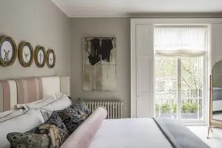 Dormitorio de color rosa pálido neutro con puertas francesas y contraventanas