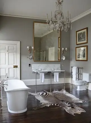 salle de bain grise avec bain autoportant, lustre et lavabo double avec comptoir en marbre