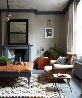Salon peint avec une palette terreuse et naturelle, une chaise longue en cuir et une table basse en bois avec coussin en cuir, un tapis à motifs crème de style marocain