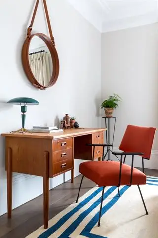 Bureau en bois, tapis bleu et crème, chaise rouge