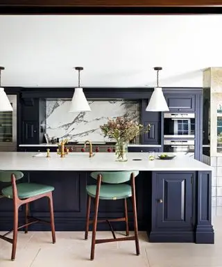 cuisine avec placards violets, plans de travail en marbre et tabourets de bar verts