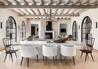 Salon blanc avec manteau de cheminée en pierre et cadres de fenêtres cintrés noirs