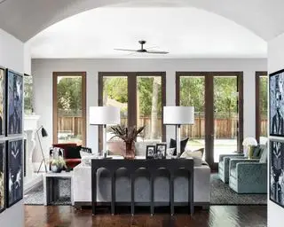 Grand séjour ouvert avec coin salon disposé autour d'une cheminée, parquet en bois sombre