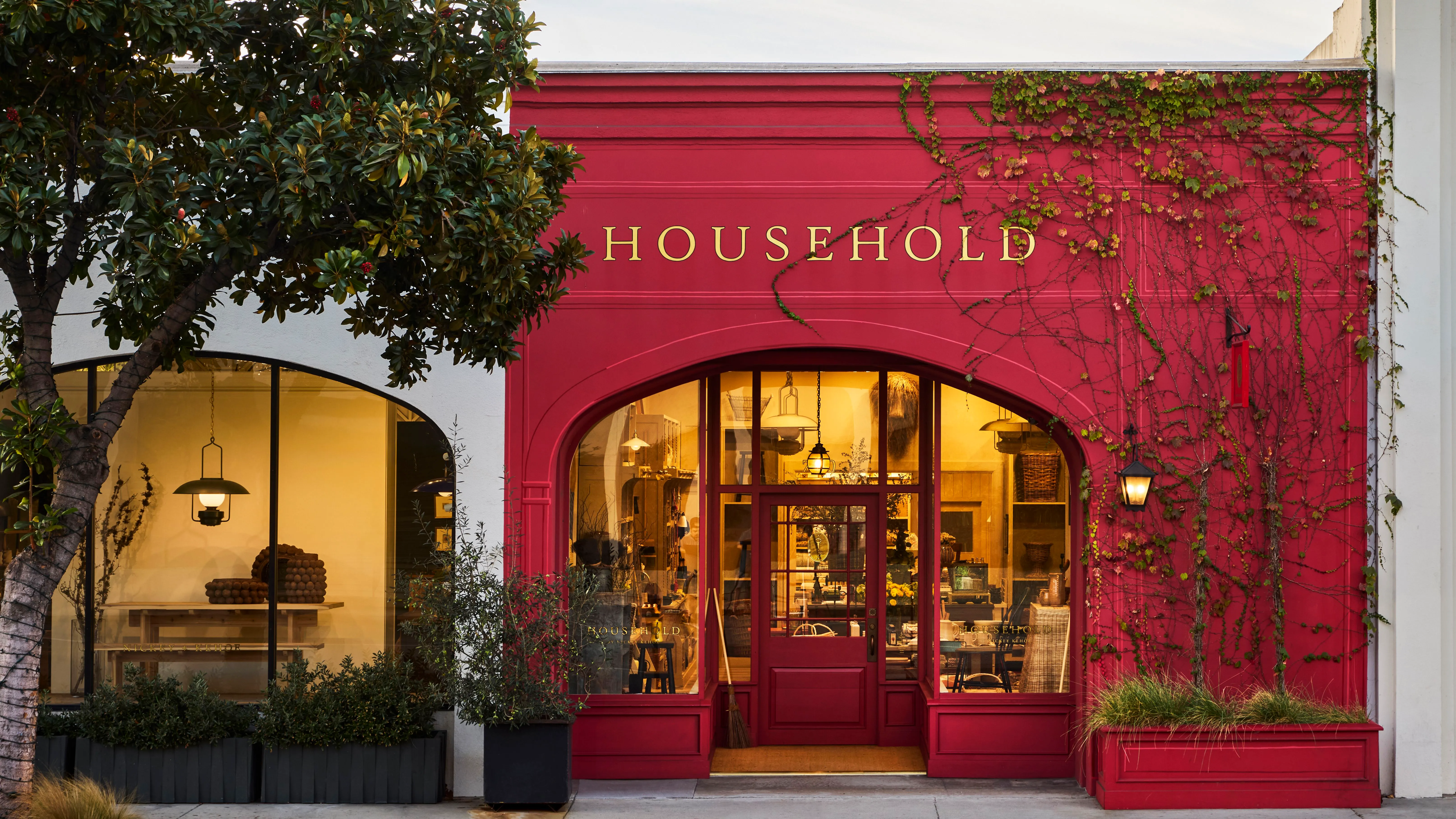 Červeně natřený obchod v LA s nápisem 'Household' napsaným jasným písmem nad proskleným předním vchodem.' loading='lazy' title=