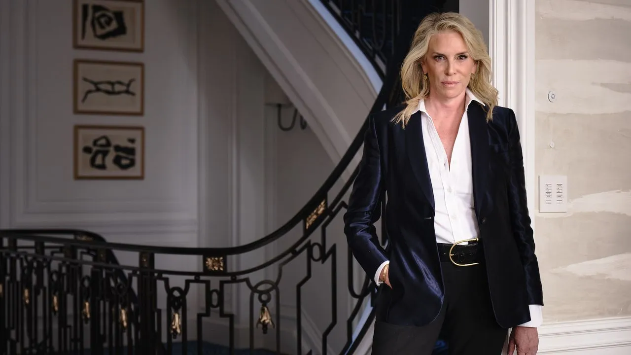 Victoria Hagan v tmavém obleku stojící u schodiště' loading='lazy' title=