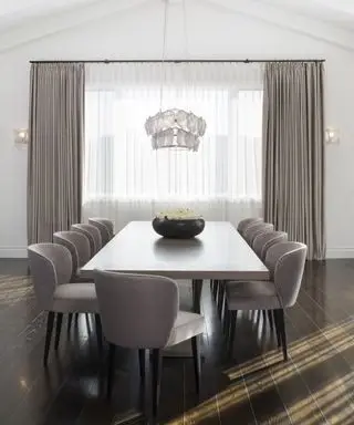 Ideas de cortinas de ventana grandes con una cortina transparente blanca debajo de cortinas grises más pesadas en un comedor