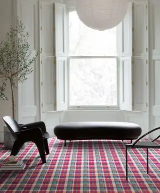 Salon blanc et moderne avec lanterne ronde blanche, meubles noirs, tapis tartan rouge vif