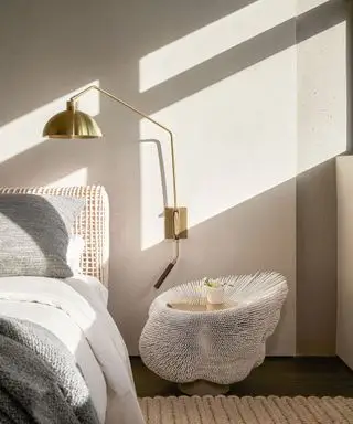 Neutrální ložnice s ratanovým čelem a odkládacím stolkem ve stylu mořské sasanky v apartmánu na pláži v Miami