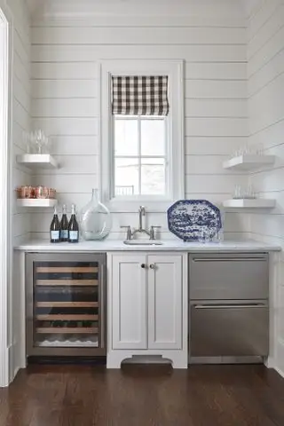 Vådbar med vask, vinkøleskab, opvaskeskuffer og vindue med ternet romersk rullegardin