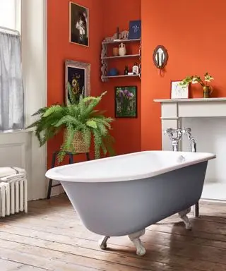 Salle de bains avec murs orange et baignoire sur roulettes peinte en gris