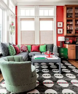 salle familiale avec murs rouges, canapé gris, fauteuil vert et tapis noir et blanc