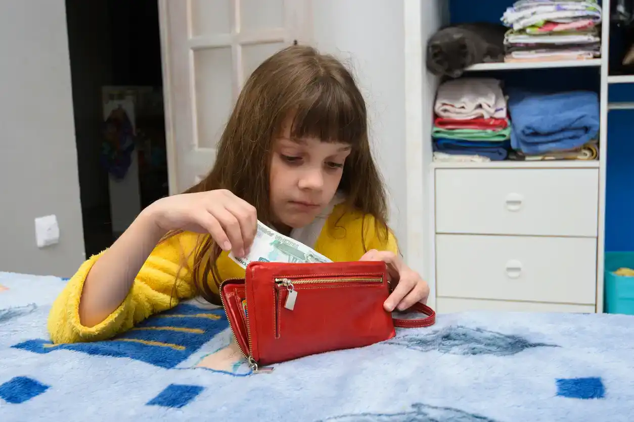 The girl opened her mothers wallet and pulls out a 20 dollar bill