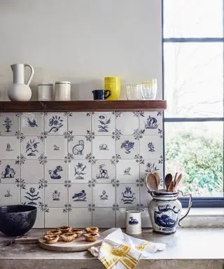 Un gros plan de carreaux de mur de cuisine bleus et blancs derrière des pâtisseries fraîchement préparées sur le plan de travail