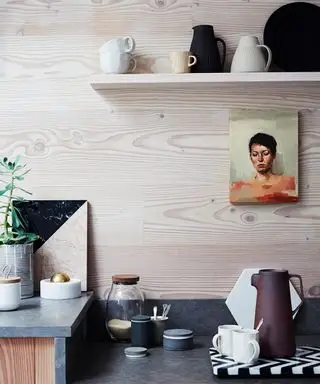Une cuisine moderne et épurée avec mur en bois et portrait à l'huile.