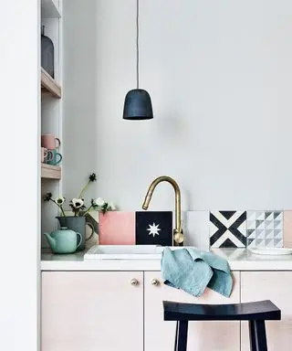 Une photo de cuisine en gros plan montrant un dosseret carrelé bleu marine, rose pâle et blanc dans un schéma neutre.