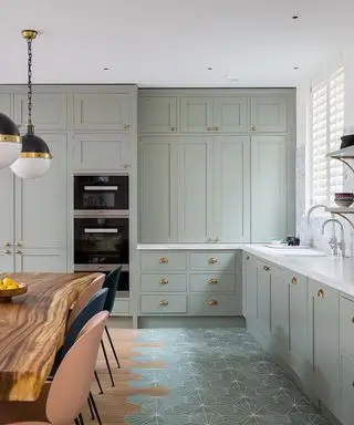 Une photo de cuisine vert menthe avec du carrelage hexagonal et une table en bois.