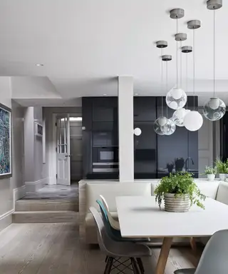 Une idée d'éclairage de cuisine avec des downlighters et des suspensions noires sur deux îlots blancs