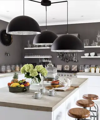 Une cuisine bleu foncé avec des idées d’éclairage de robinet et d’étagère dorées.