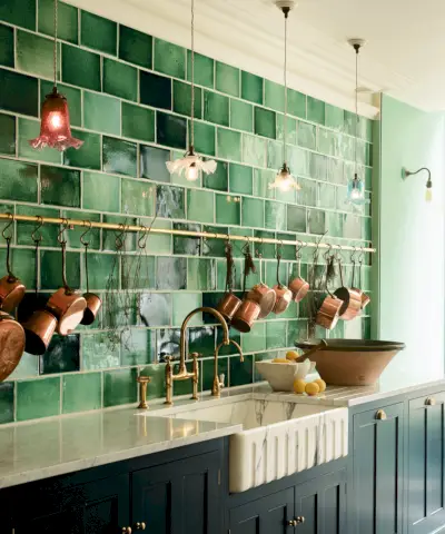 Idées d'éclairage de cuisine avec des abat-jour blancs surdimensionnés suspendus au-dessus d'un îlot avec un comptoir en marbre, des armoires bleues et des tabourets de bar en cuir marron