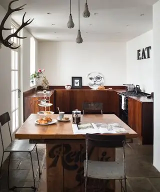Idées de cuisine en forme de U illustrées par une cuisine originale en bois sombre avec des murs blancs et un sol en dalles d'ardoise.