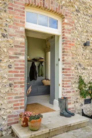 L'emplacement est important lors de la conception d'un vestiaire comme celui-ci comprenant un grand paillasson et un banc avec rangement intégré.