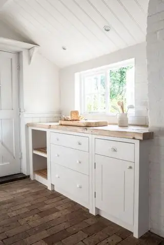 Vestiaire avec sol en brique, placards blancs et fenêtre pittoresque pour la ventilation