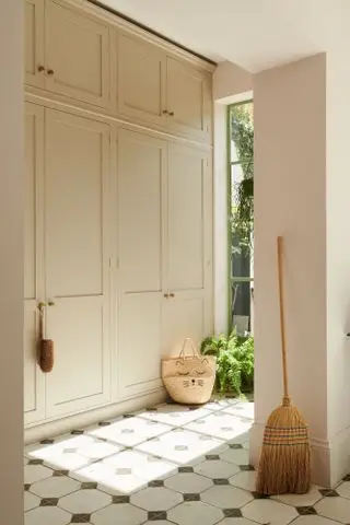 Un vestiaire avec des placards crème du sol au plafond et des murs rose foncé