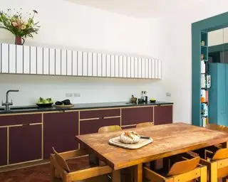 Cocina moderna con gabinetes de dos tonos y mesa y sillas de madera.