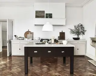 Une cuisine blanche traditionnelle avec une suspension tendance sur un îlot peint en noir.