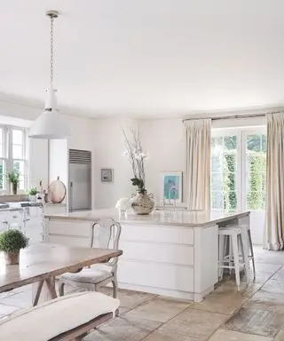 再生石畳の床と設備の整ったキッチンを備えたオープンプランのキッチン ダイナー。