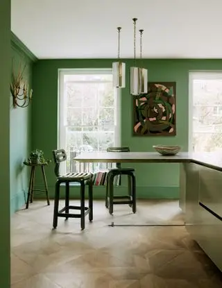 Idées de cuisine vert moyen avec des murs verts, des œuvres d'art abstraites, du parquet et un îlot de cuisine péninsule.