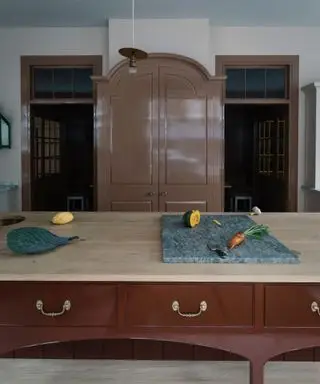 Îlot de cuisine rouge brillant avec comptoir en marbre et placard garde-manger rose brillant assis derrière