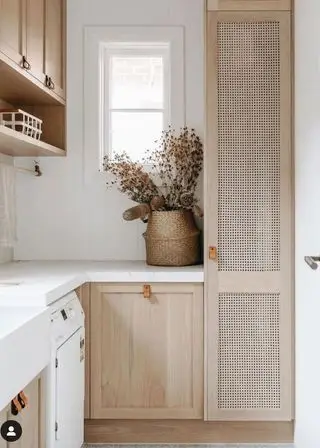 Neutrální nápady na malou prádelnu se skříňkami s texturou z přírodního dřeva a sušenými květinami s bílou pracovní deskou a pozadím.