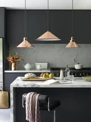 Cuisine noir mat avec surfaces en marbre blanc et lampes basses en laiton