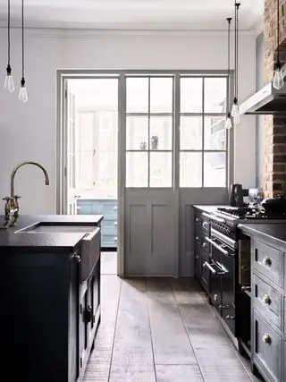 Idées de cuisine en noir et blanc de style shaker avec des notes de beauté rustique telles que la cuisinière et le four traditionnels et les luminaires en laiton