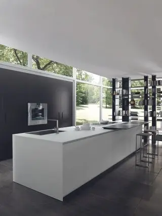 Cuisine élégante et moderne avec un îlot de cuisine blanc et des planchers et armoires en bois sombre qui ne font qu'un avec le mur.