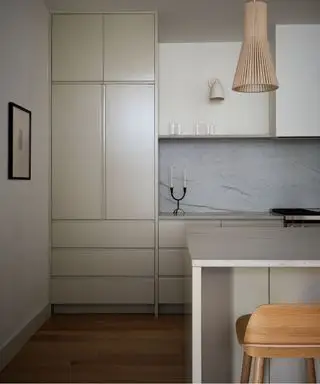 Cocina neutra con lámpara colgante de ratán y taburete de madera con isla de cocina.