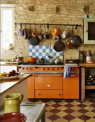 Cuisinière orange dans une cuisine rustique avec carrelage en damier