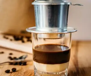 wietnamska kawa z finem na wierzchu i fasolą w tle