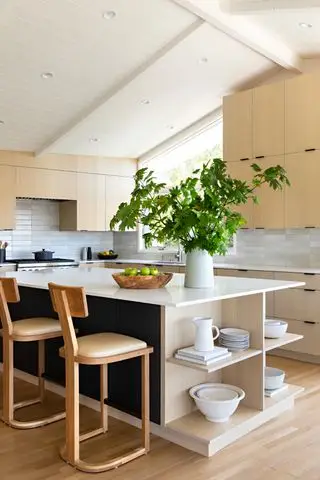 Cocina de madera con gran isla con estanterías y vegetación.