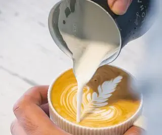 바리스타는 카푸치노, 라떼 아트를 만들기 위해 에스프레소 커피에 우유를 붓습니다.