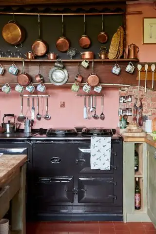 Aga dans une cuisine d'une vieille maison avec des casseroles en cuivre suspendues au-dessus