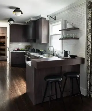cuisine en bois sombre avec murs blancs et disposition péninsulaire