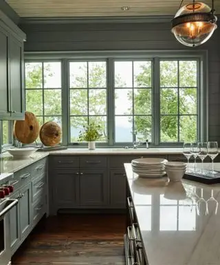 Cocina moderna de estilo rústico pintada en verde suave con encimeras de piedra blanca