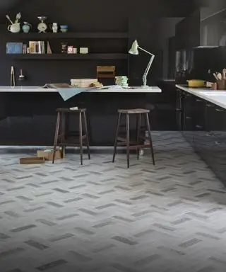 Un agencement de cuisine sombre avec un exemple d'idées de revêtements de sol de cuisine en vinyle effet bois multicolores posés dans un style à chevrons.