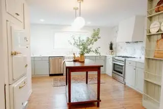 机を再利用して作った小さなアイランドと大きな冷蔵庫を備えたキッチン