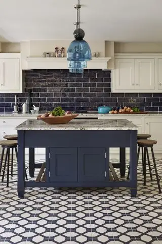 Uma cozinha azul e branca com piso geométrico e um design de ilha de cozinha quadrada e balcão para café da manhã.